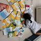 A student laying on the ground with books around her as a way to participate in the flaunt wealth challenge.
